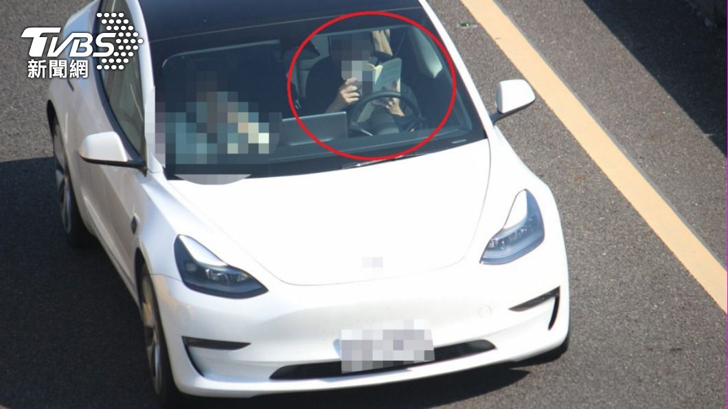 A driver appeared absorbed in his book while driving on the freeway. (TVBS News)